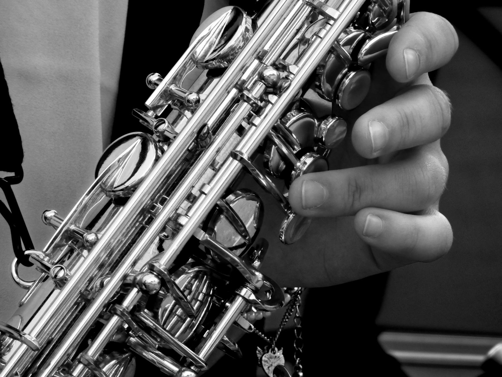 person holding saxophone in gray scale photography